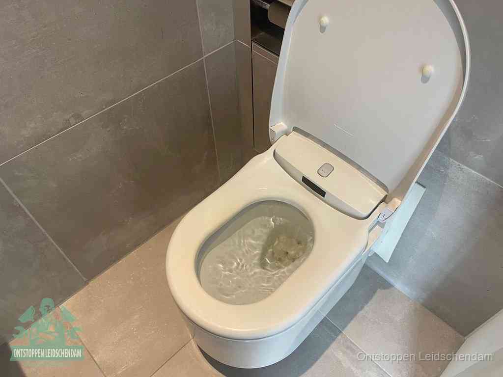 Een toiletpot vol troebel water met drijvend papier en restanten, de meest voorkomende oorzaak van een verstopte wc in Leidschendam