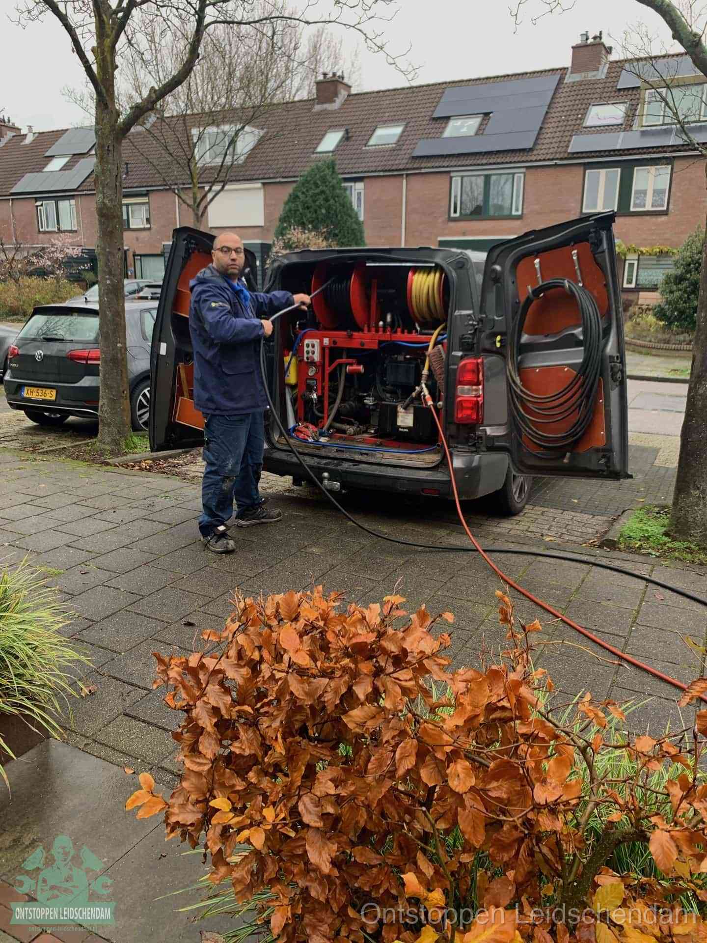 Monteur met rioolreinigingsbus levert rioolservice in de wijk in Leidschendam