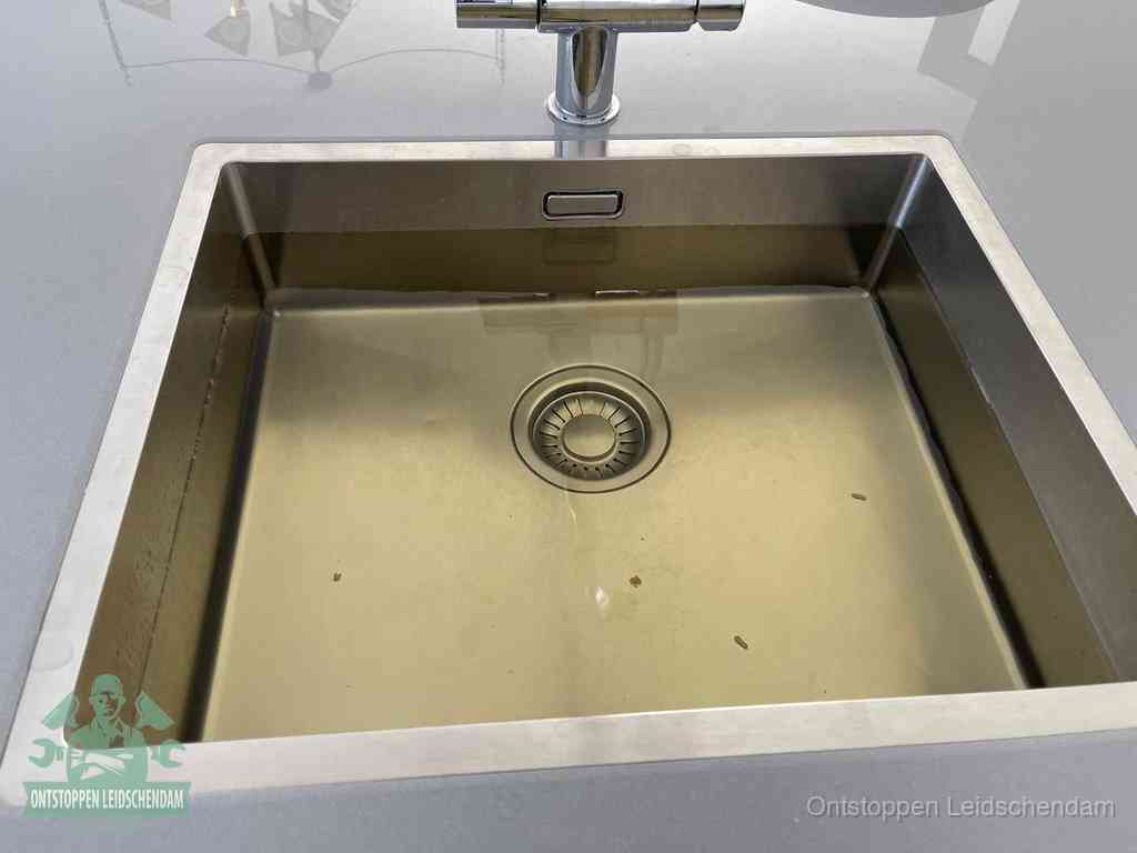 Stilstaand water in een rvs spoelbak dat niet wegloopt, een duidelijk signaal van een gootsteenverstopping in Leidschendam