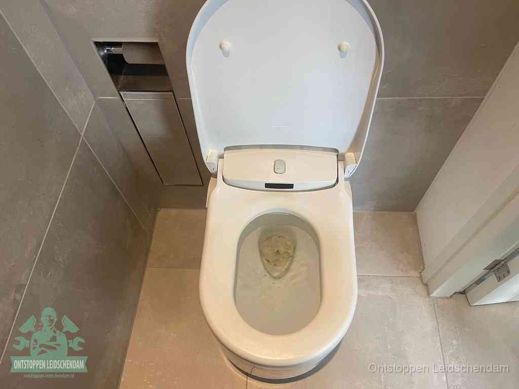 Een wit hangtoilet waarin een prop wc-papier op het water blijft drijven, een duidelijk signaal van een verstopte wc in Leidschendam