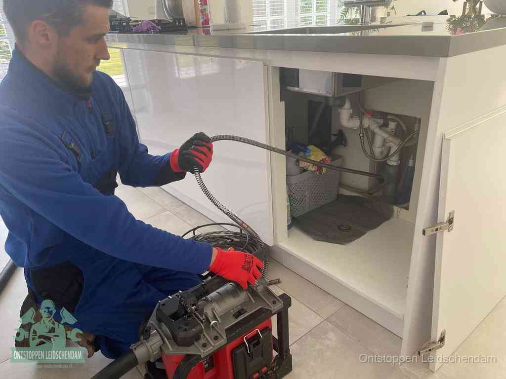 Een monteur reinigt de keukenafvoer grondig met een veermachine om terugkerende gootsteenverstoppingen te voorkomen in Leidschendam